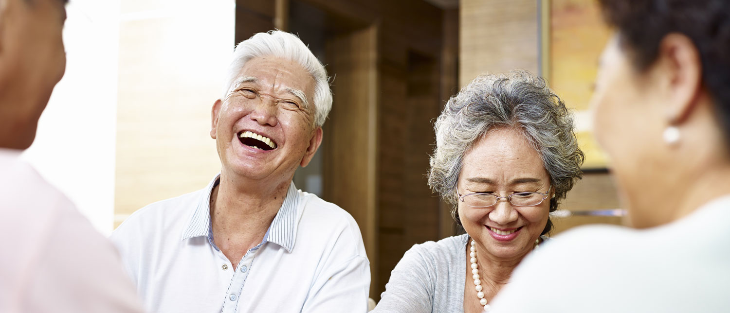 happy senior couple laughing with friends at table