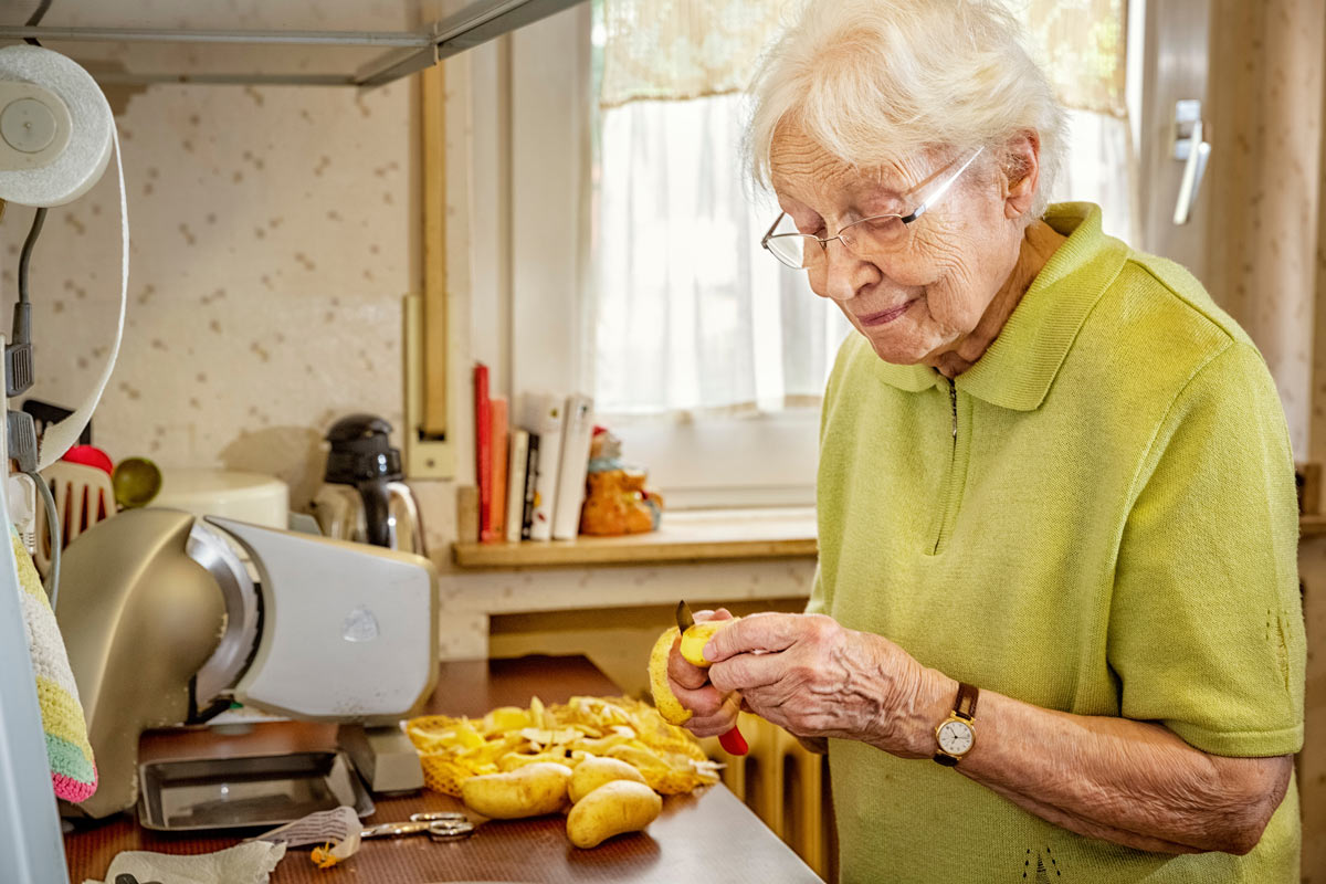 VRS Ross Place Senior peeling potatoes for cooking in assisted living suite